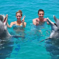 Dos turistas disfrutando de su encuentro con los delfines en la Academia de Delfines de Curaçao.