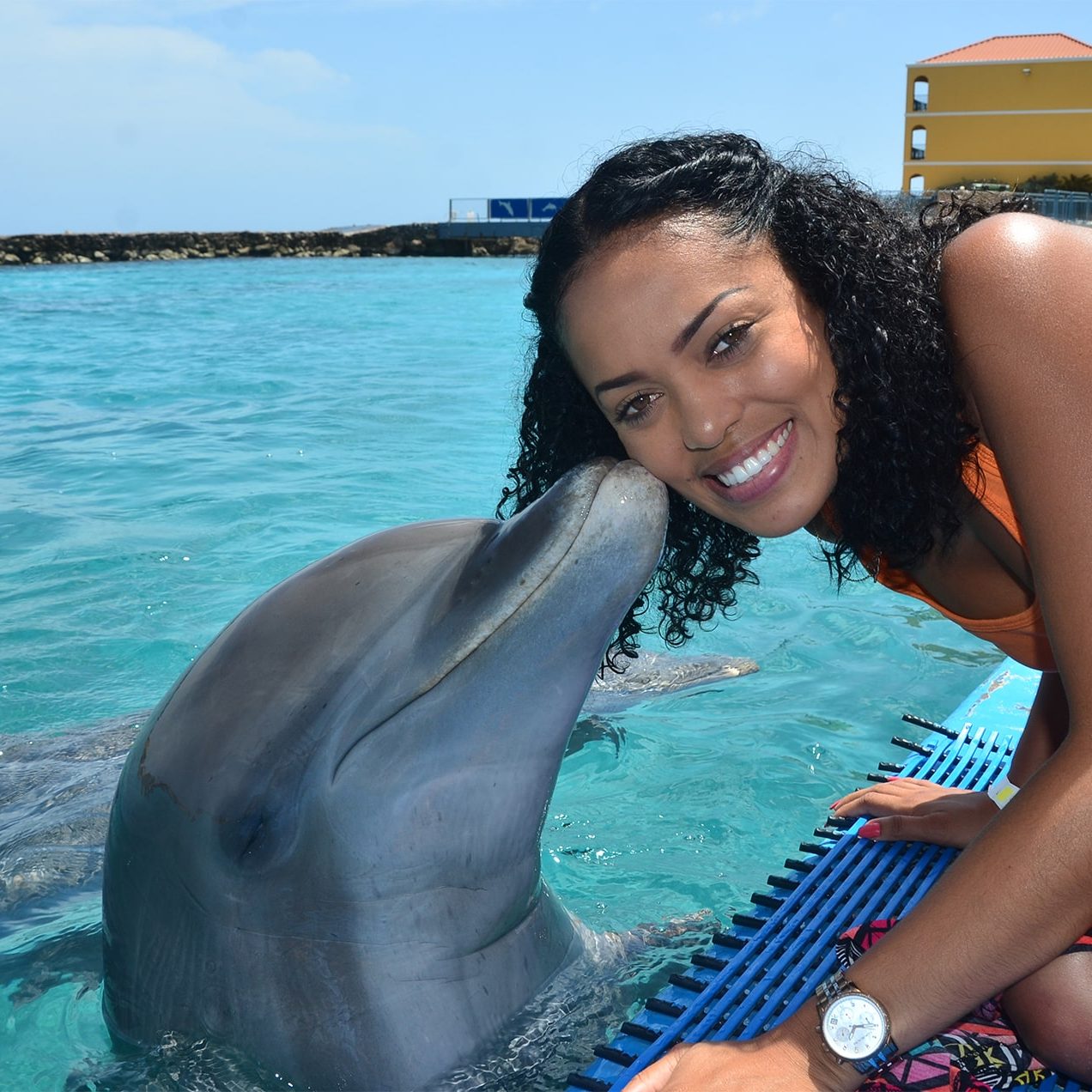 Vrouwelijke toerist ontvangt een kus van een dolfijn bij de Dolphin Academy Curaçao.
